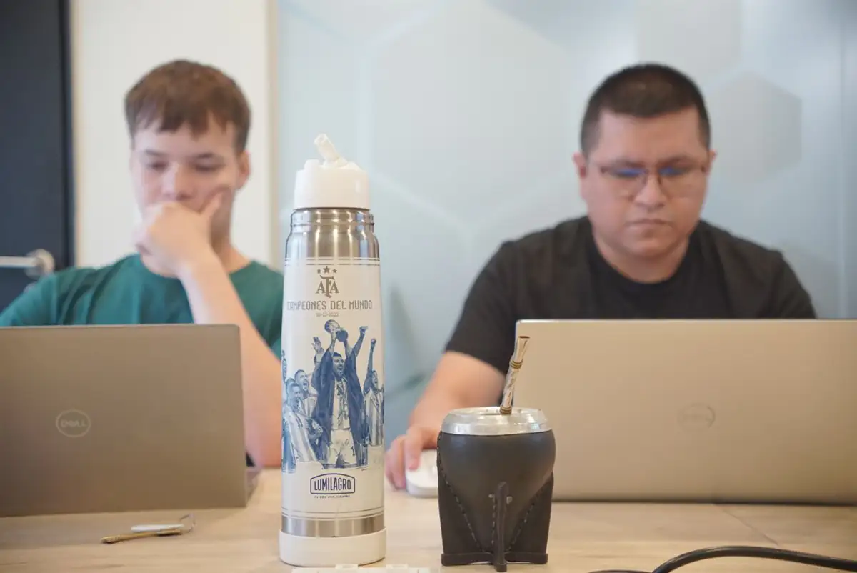 Dos personas del equipo trabajando en la oficina, con el mate en la mesa